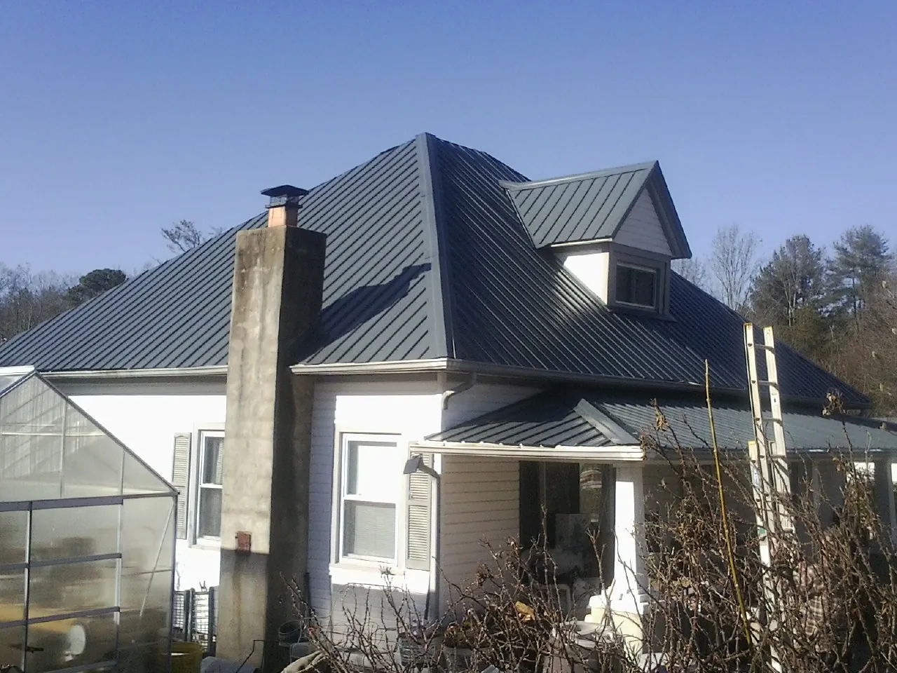 Dark blue standing seam metal roof on a white farmhouse with dormer — Slate & Tile Roof Repair by Roofing Brothers in Hazel Green