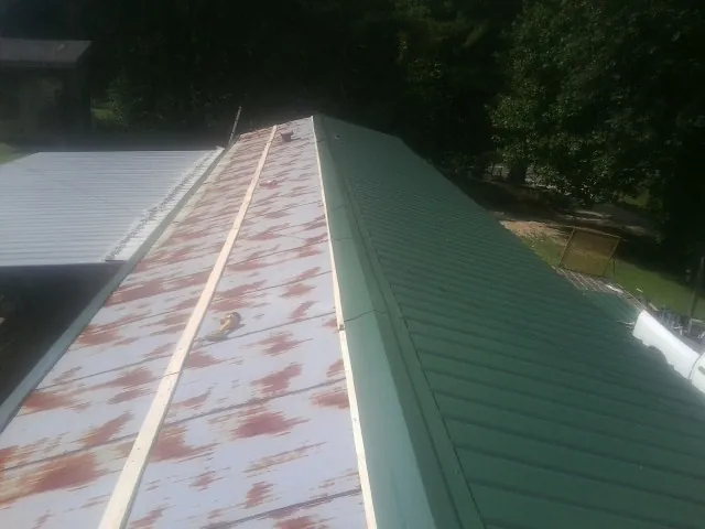 Old rusted panels beside newly installed green metal roofing — Wind Damage Roof Repair by Roofing Brothers in Hazel Green