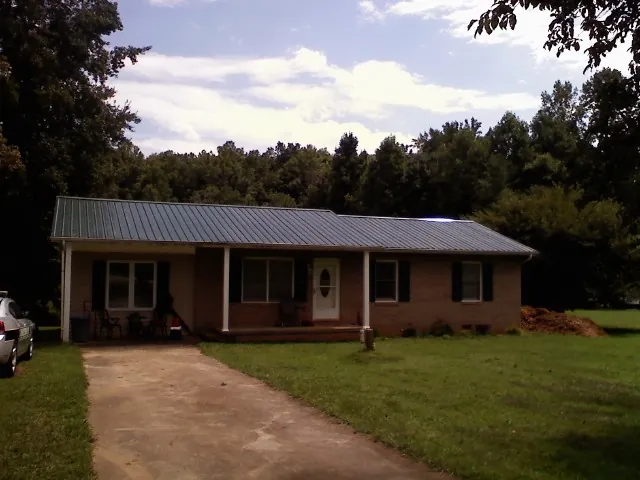 Dark green metal roof on a brick ranch with a covered porch in Hazel Green