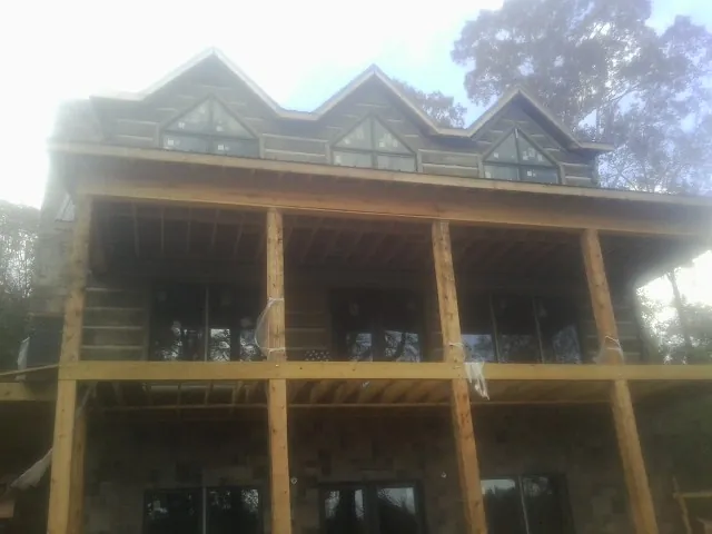 Dormers and porch framing on a large log home under construction — Roof Coating work by our crew in Hazel Green