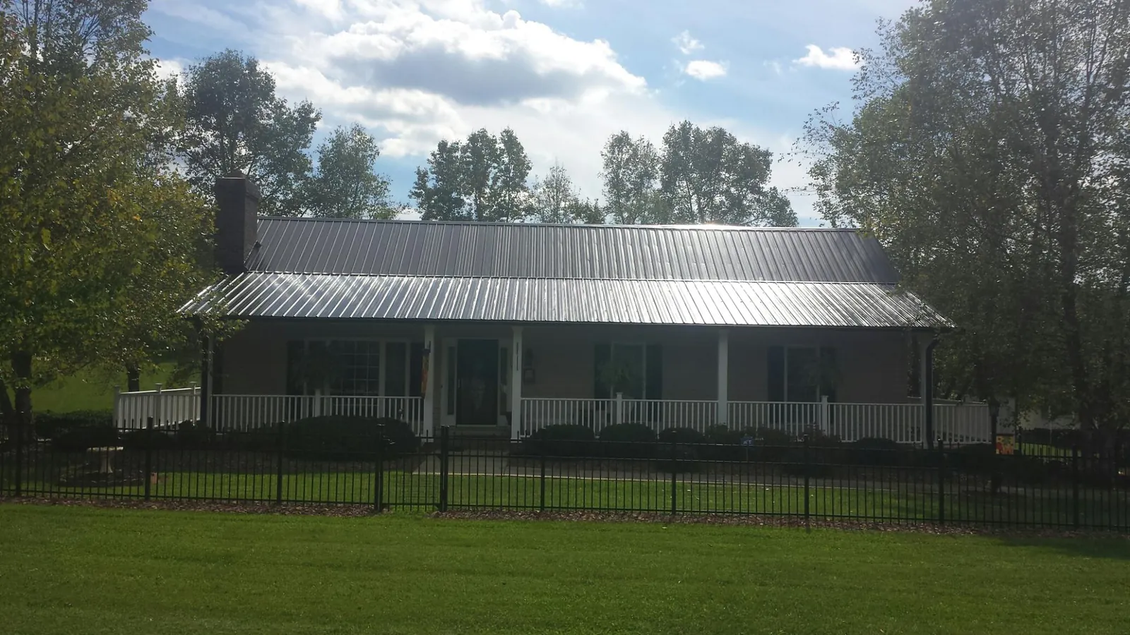 Gray metal roof on a brick ranch with a full width front porch — Gutter Guard Installation work by our crew in Hazel Green