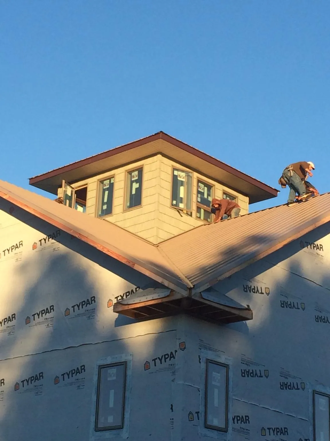 Roofers working around a rooftop cupola on a new metal roof at sunset — Roof Waterproofing in Hazel Green by Roofing Brothers